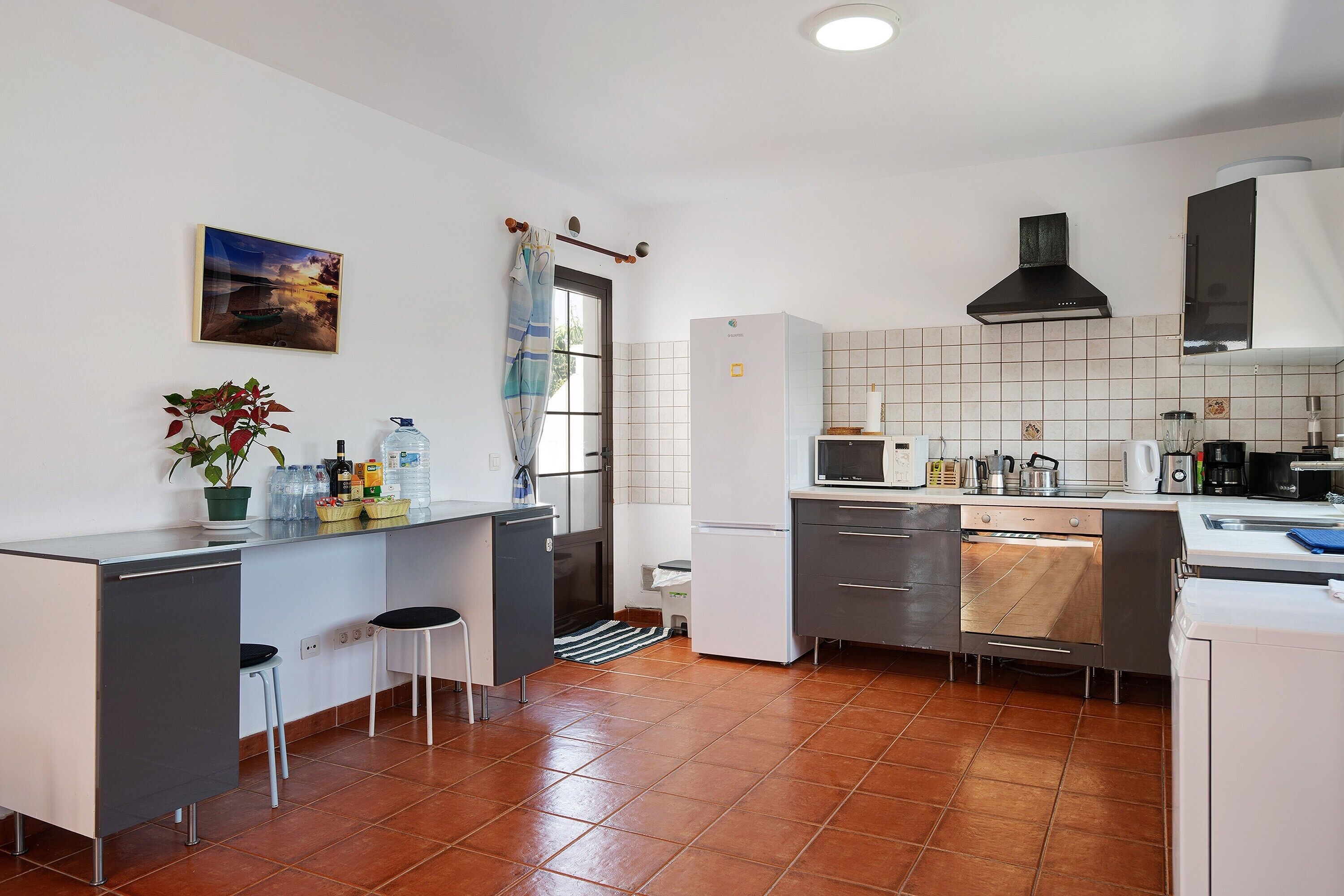 A modern kitchen with a tiled backsplash, a built-in oven, and a microwave.