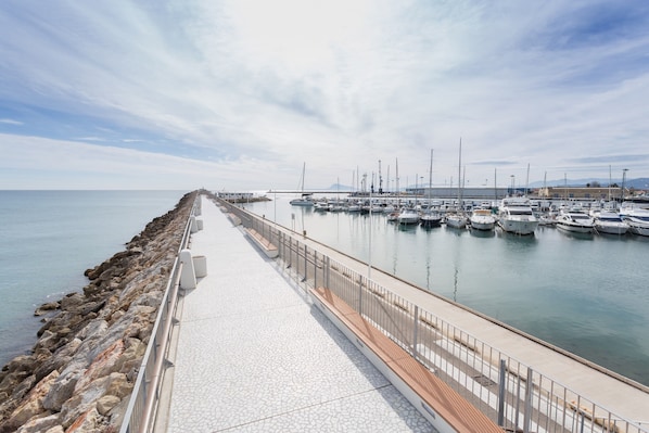 Un port de plaisance avec des bateaux amarrés, une jetée en pierre et un ciel dégagé.