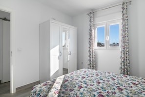 Un dormitorio con cama, armario, ventana con cortinas y puerta.