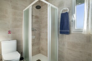 Een badkamer met een douche met glazen wand, een toilet en een handdoekhouder.