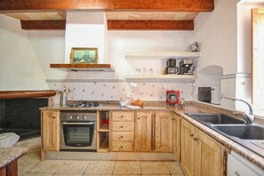 A kitchen with wooden cabinets, a gas stove, a microwave, and a coffee maker.