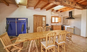 A dining area with a wooden table and chairs, a kitchen with a stove and sink, and a blue door.