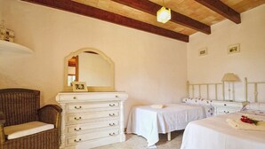Een slaapkamer met een dressoir, twee eenpersoonsbedden, een stoel en een spiegel.