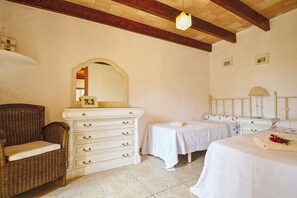 A bedroom with a dresser, two single beds, a chair, and a mirror.