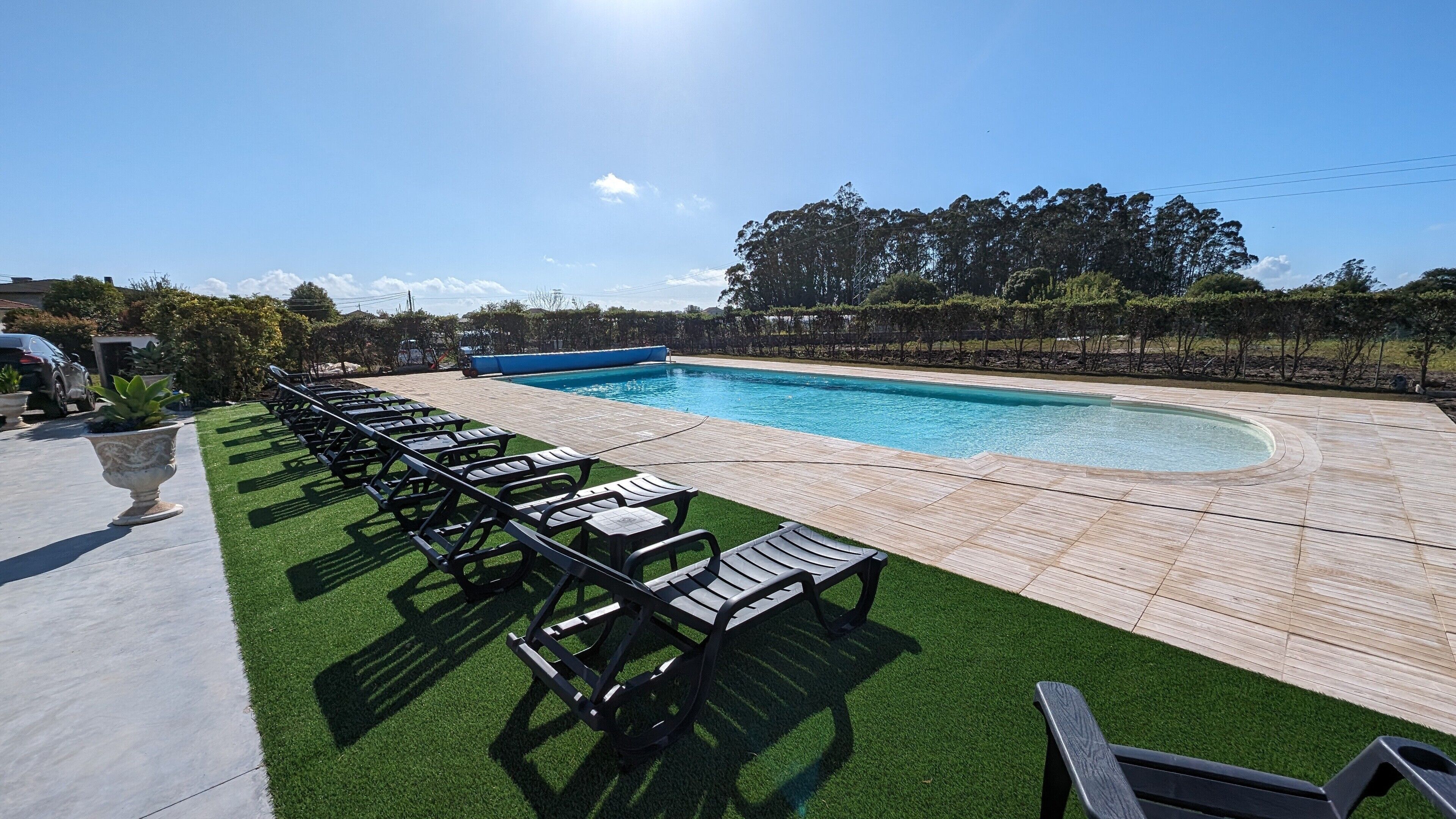 A swimming pool with lounge chairs and a paved deck.