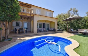 A house with a swimming pool, outdoor furniture, and a patio area.
