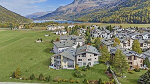 A residential area with houses, a lake, and mountains in the background. - 4-room apartment in the loft. (Sils/Segl Maria)