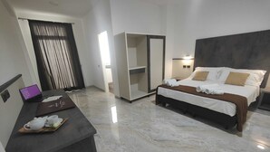 A modern hotel room with a bed, bedside table, and a desk with a laptop and teapot. - HOTEL EBOLI (Eboli)
