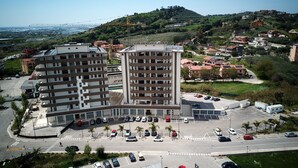 A multi-story parking structure with a central pedestrian walkway, surrounded by a mix of residential buildings and greenery. - HOTEL EBOLI (Eboli)