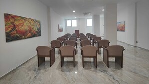 A spacious gallery with rows of chairs facing a large abstract painting on the left. - HOTEL EBOLI (Eboli)