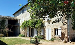 Experience a traditional stay in a historic building with a rustic charm, surrounded by a serene lawn and lush greenery.