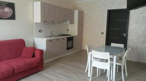 A compact living space with a kitchenette, a dining area, and a red sofa.