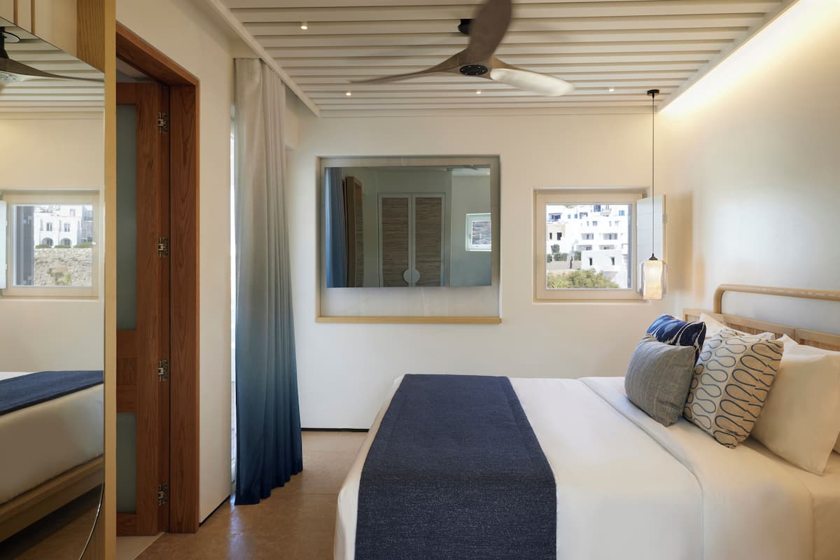 Un dormitorio moderno con una cama grande, ventilador de techo y vistas al exterior.