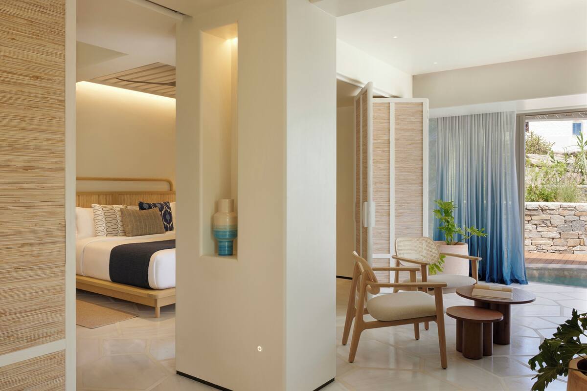 Habitación de hotel moderna con cama, zona de estar y vistas al exterior.
