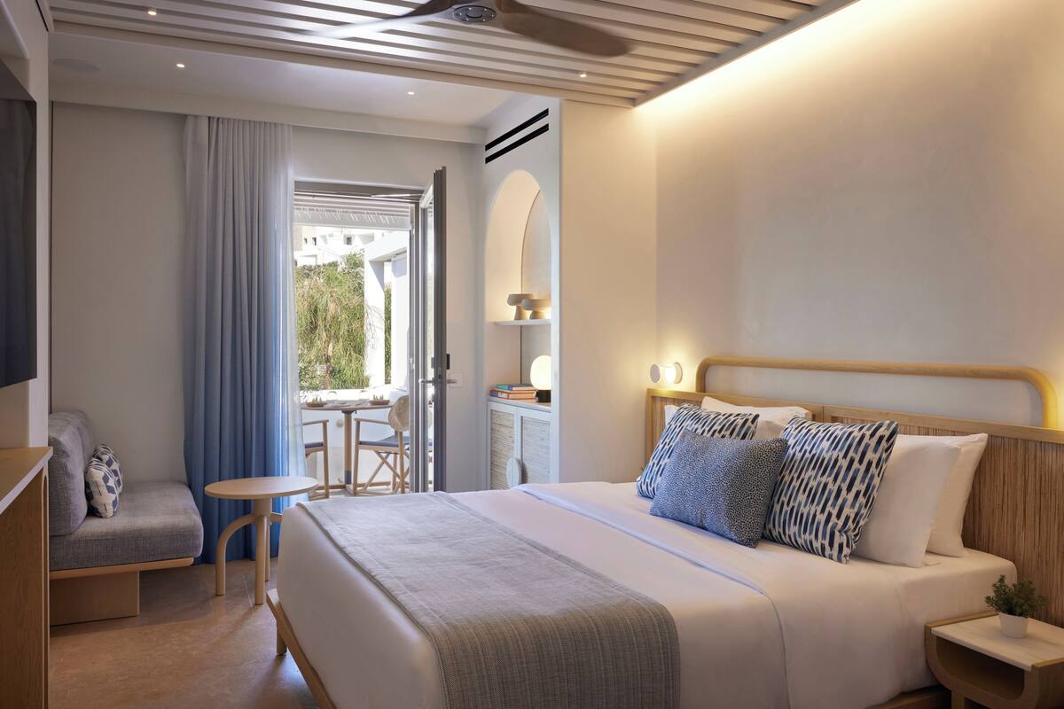 Una habitación de hotel moderna con una cama grande, una zona de estar y una pequeña mesa.