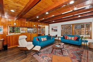 A wooden interior with a sofa, armchair, and a small table. - Wren's Cottage by Destination Big Bear: Pet Friendly! Spa! Located in the Summit Lake Neighborhood! Infinity Game Table! Fenced Yard! Playgym! Horseshoe Pit! (Big Bear Lake)