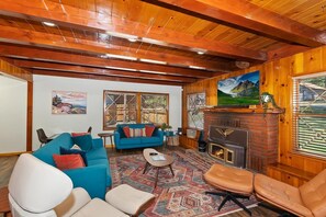 A cozy living room with a fireplace, blue sofa, and leather chairs. - Wren's Cottage by Destination Big Bear: Pet Friendly! Spa! Located in the Summit Lake Neighborhood! Infinity Game Table! Fenced Yard! Playgym! Horseshoe Pit! (Big Bear Lake)