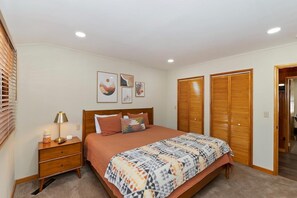 A bedroom with a bed, bedside table, lamp, and artwork on the wall. - Wren's Cottage by Destination Big Bear: Pet Friendly! Spa! Located in the Summit Lake Neighborhood! Infinity Game Table! Fenced Yard! Playgym! Horseshoe Pit! (Big Bear Lake)