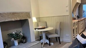 Una sala de estar con un sofá gris, una mesita redonda y una chimenea.