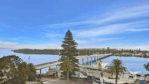 Une zone côtière avec un pont, des bâtiments donnant sur le front de mer et un ciel dégagé.