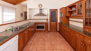 Eine Küche mit Holzausstattung, einer Edelstahlspüle, einem Einbauofen und einer gefliesten Spritzschutzwand.