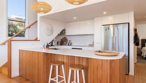 Enjoy casual dining at the central island with two stools, complemented by a stainless steel refrigerator, oven, and sink.