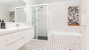 A bathroom with a white vanity, a glass shower enclosure, and a tiled floor.
