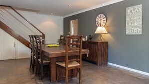 A dining area with a wooden table and chairs, a clock on the wall, and a lamp.