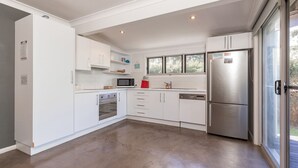 A modern kitchen with white cabinetry, stainless steel appliances, and a large window providing natural light.