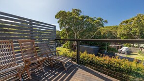 A wooden deck with two wooden chairs and a metal railing.