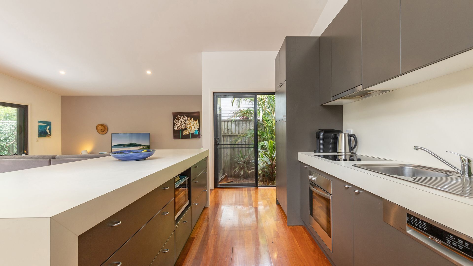 A modern kitchen with a large island, a built-in oven, and a sleek sink.