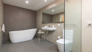Un baño moderno con una bañera independiente, un lavamanos pedestal y un inodoro.