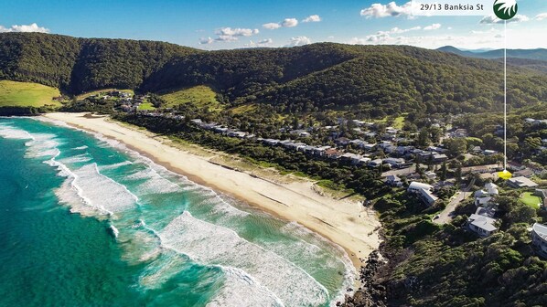 Enjoy stunning beachfront views and serene surroundings at this coastal property, featuring lush greenery and rolling hills.