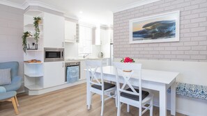 Enjoy meals in the well-equipped kitchen with microwave, adjacent to a dining area with a table and chairs.