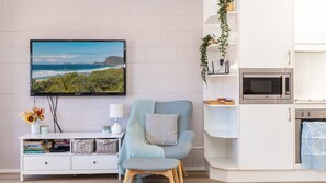 Relax in this stylish living room with a flat-screen TV, comfortable armchair, and convenient shelving unit.