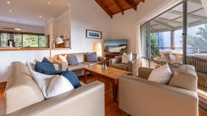 A modern living room with leather sofas, a wooden coffee table, and a large TV.