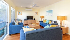 A modern living room with two sofas, a coffee table, a TV, and a ceiling fan. - Point Break @ Boomerang Point (Boomerang Beach)