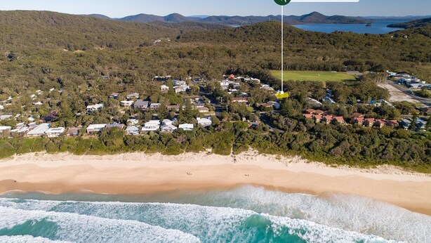 An aerial view of a coastal residential area with houses, a beach, and a forested hill. - Point Break @ Boomerang Point (Boomerang Beach)