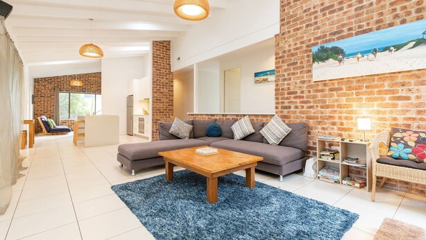 A modern living room with a sofa, coffee table, and a brick wall. - Splash @ Elizabeth Beach (Elizabeth Beach)