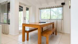 A wooden table with a bench in a bright room with white walls and tiled flooring. - Splash @ Elizabeth Beach (Elizabeth Beach)