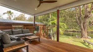 Eine moderne Hütte mit Holzterrasse, einer Couch und einem Esstisch.
