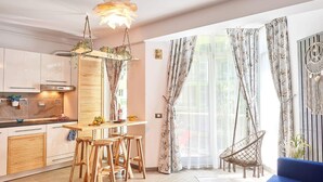 A modern kitchen with a wooden island, hanging chairs, and a blue sofa. - Luxury Alezzi (Navodari)