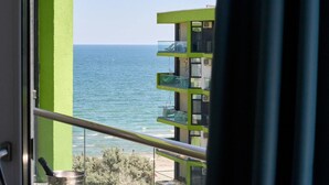 A view of the sea from a balcony with a green building in the background. - Luxury Alezzi (Navodari)