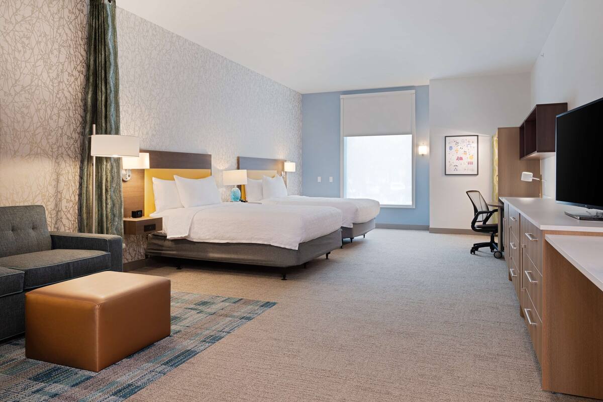 Ein Hotelzimmer mit Bett, Schreibtisch, Stuhl und Fernseher.
