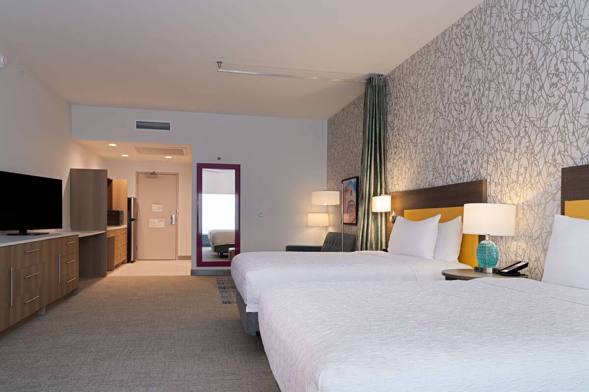Ein Hotelzimmer mit einem großen Bett, einem Fernseher, einem Schreibtisch und einem Badezimmer.