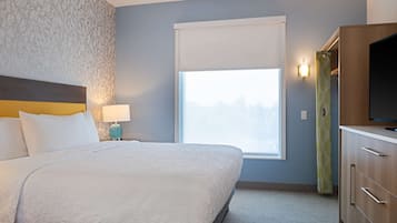 Una habitación de hotel con una cama, una mesita de noche, una lámpara, una ventana y un televisor.
