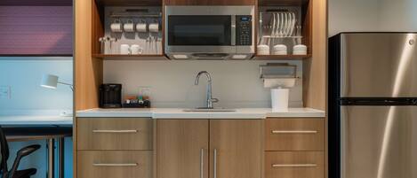 A compact kitchen with a microwave, coffee maker, and stainless steel refrigerator.