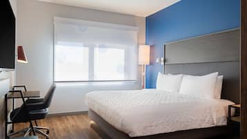 Una habitación de hotel moderna con una cama grande, un escritorio, una silla y una ventana con vistas.