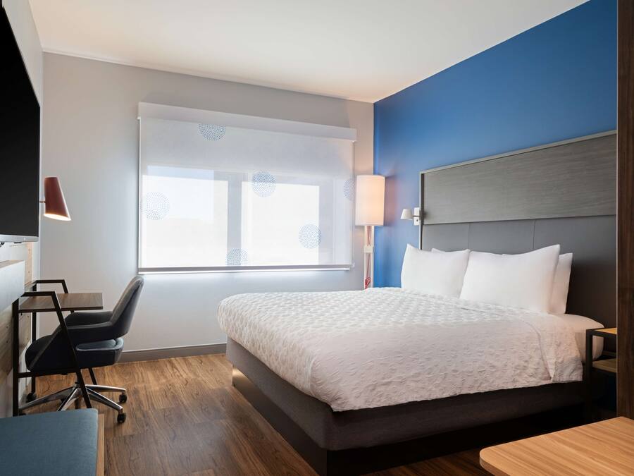 Una habitación de hotel moderna con una cama grande, un escritorio, una silla y una ventana con vistas.