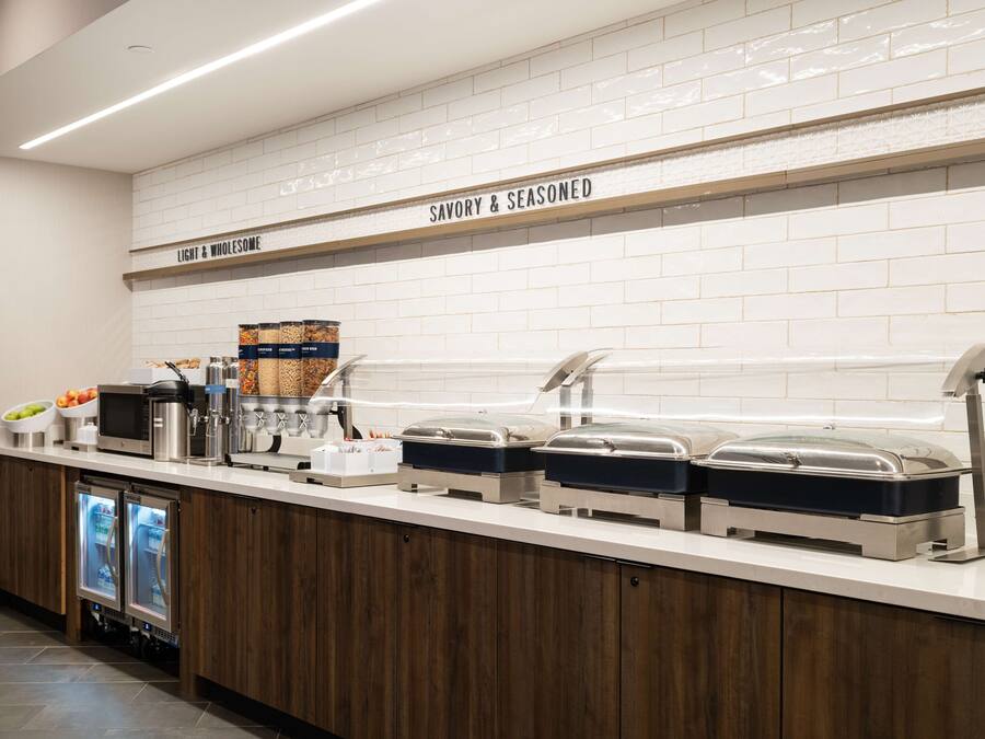 Un'area buffet con sezioni segnalate per alimenti 'Light & Wholemeal' e 'Savory & Seasoned', dotata di diversi distributori automatici di cibo e una macchina per il caffè.